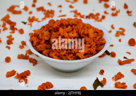 Maccheroni piccanti e saporiti in una ciotola su fondo bianco. I maccheroni secchi hanno una sensazione diversa quando vengono consumati come snack. Foto Stock