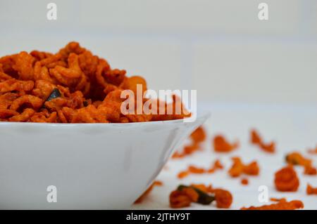 Maccheroni piccanti e saporiti in una ciotola su fondo bianco. I maccheroni secchi hanno una sensazione diversa quando vengono consumati come snack. Foto Stock