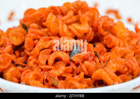 Maccheroni piccanti e saporiti in una ciotola su fondo bianco. I maccheroni secchi hanno una sensazione diversa quando vengono consumati come snack. Foto Stock