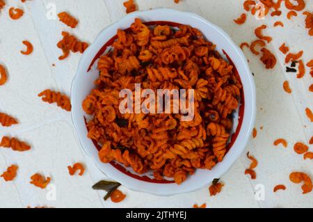 Maccheroni piccanti e saporiti in una ciotola su fondo bianco. I maccheroni secchi hanno una sensazione diversa quando vengono consumati come snack. Foto Stock