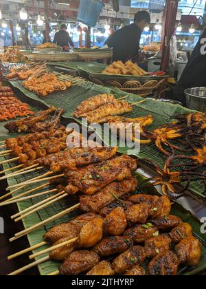 Pollo al barbecue, gamberi, polpo e aragosta su spiedini di bambù in una bancarella di cibo di strada a Bangkok, Thailandia Foto Stock
