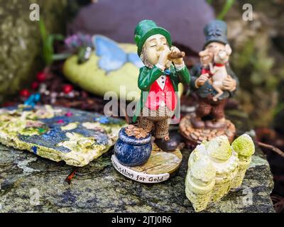 Regali tra cui piccole statue di leprechauns lasciate dai visitatori in un "percorso delle fate", Irlanda del Nord. Foto Stock