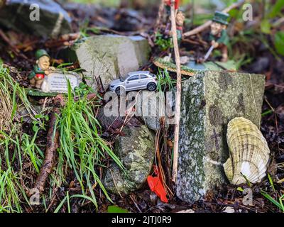 Regali tra cui piccole statue di leprechauns e macchinine lasciate dai visitatori in un "percorso delle fate", Irlanda del Nord. Foto Stock