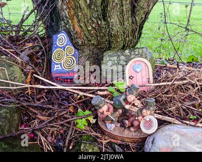 Regali tra cui piccole statue di leprechauns lasciate dai visitatori in un "percorso delle fate", Irlanda del Nord. Foto Stock