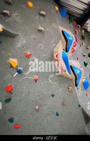 Parete bouldering arrampicata artificiale roccia che mostra impugnature di vari colori. Stile di vita sportivo e attivo. Foto Stock