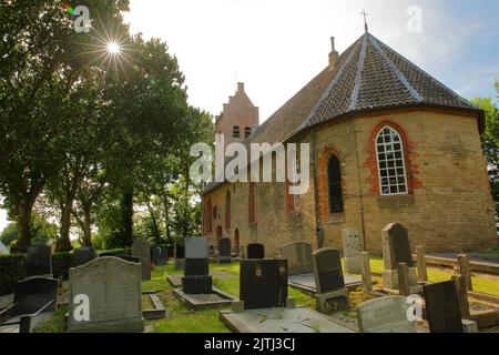 La chiesa riformata (Hervormde Kerk), situata sul tumulo di Hogebeintum, Friesland, Paesi Bassi, con tombe in primo piano Foto Stock