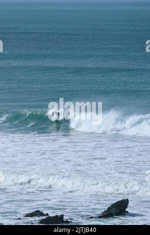 Un surfista solista che guida un'onda a Fistral Bay a Newquay in Cornovaglia in Inghilterra nel Regno Unito. Foto Stock