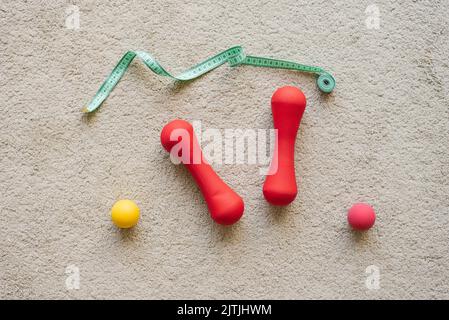 Set piatto di manubri rossi, centimetri, attrezzature sportive, articoli fitness, vista dall'alto Foto Stock