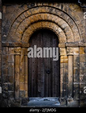 Uno scatto verticale di un antico castello porta in legno circondata da pietra Foto Stock