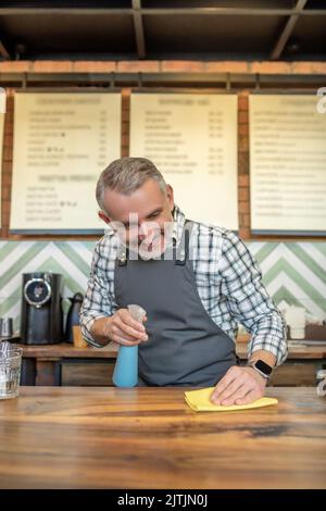 Barista allegro e professionale che pulisce la sua area di lavoro Foto Stock