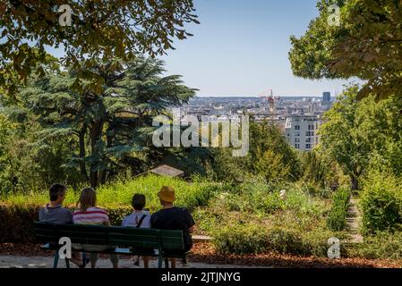 Persone sedute su una panchina che domina il panorama della città, Pere Lachaise Cemetery, Parigi, Francia Foto Stock