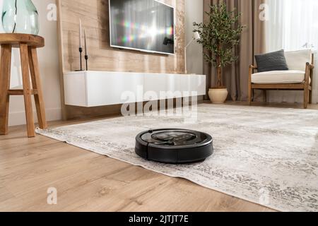 Aspirapolvere robotizzato sul pavimento in un accogliente e moderno soggiorno Foto Stock