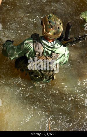 Esperienza militare completa - un giorno commando - correre attraverso l'acqua con la replica automatica del fucile Foto Stock
