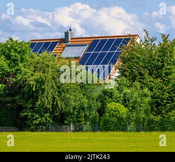 Casa moderna con fotovoltaico e collettori per energia solare termica sul tetto per la produzione di energia alternativa Foto Stock