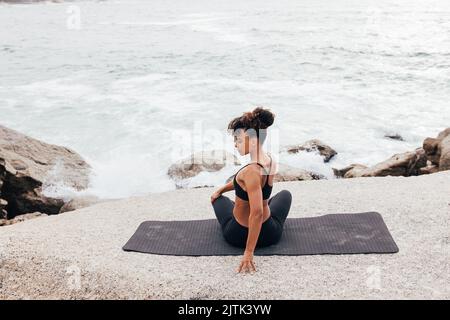 Vista posteriore della giovane atleta che si riscalda il corpo dall'oceano Foto Stock