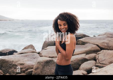 Donna felice in abbigliamento sportivo in piedi con gli occhi chiusi da oceano Foto Stock