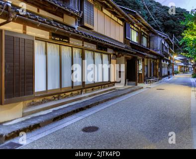 Grandi finestre e tradizionale edificio Giapponese lungo una strada vuota al tramonto Foto Stock