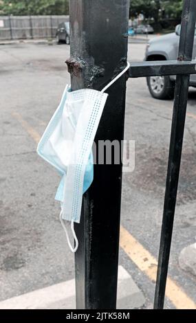 Una maschera facciale blu è appesa scartata su una recinzione a Chicago, Illinois, il 16 luglio 2022. Foto Stock