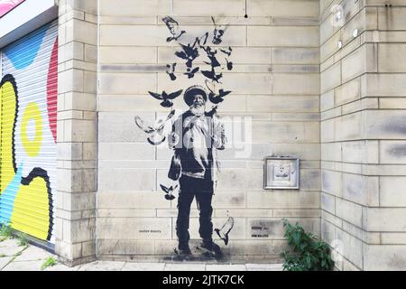 Barry Roots, il 'bird man', di Roots Record Shop, un DJ e musicista reggae, su John Street, una delle icone di Bradford celebrata nella Street art Foto Stock