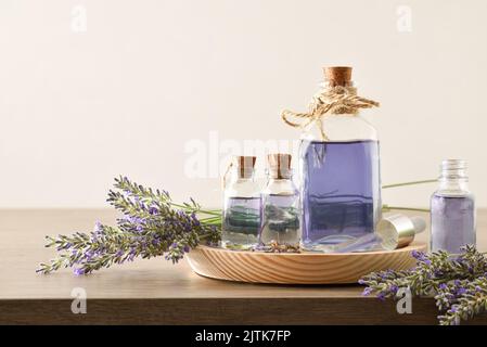 Profumo naturale con fondo in essenza di lavanda in bottiglie e bouquet di punte intorno su tavolo di legno e fondo bianco isolato. Vista frontale. H Foto Stock