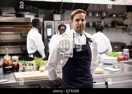 Ritratto di chef fiducioso in piedi in cucina ristorante Foto Stock