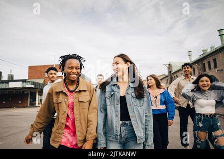 Felici giovani amici multirazziali che camminano sulla strada della città Foto Stock