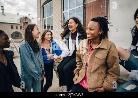 Felice multirazziale giovani amici che parlano fuori edificio Foto Stock
