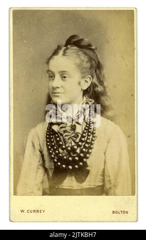 Originale ritratto in studio di una ragazza vittoriana adolescente, con lunghi capelli ondulati sciolti, della CDV vittoriana (carte de visite o Visiting card) ma legata dal viso, indossa una camicetta con un ruff e una spilla frontali e diversi splendidi anelli di perline che sono probabilmente fatti di jet (vedi la principessa Louise Duchessa Argyll, che indossa perline simili in un ritratto datato 1870). Dallo studio di W. Currey, Bark Street, Bolton, Lancashire, Inghilterra, Regno Unito all'inizio degli anni '1870 Foto Stock