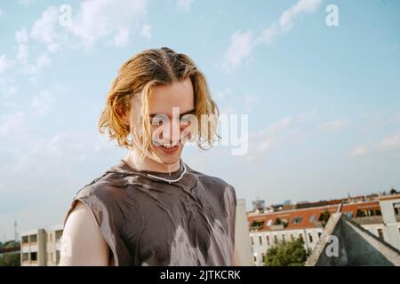 Felice giovane uomo con capelli biondi contro il cielo Foto Stock