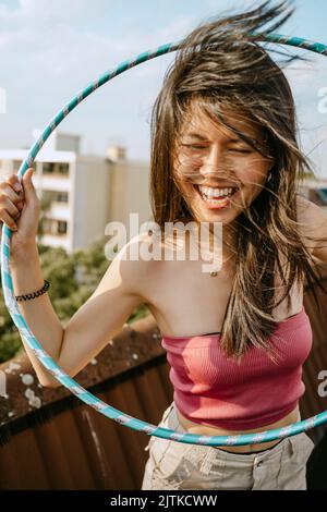Felice giovane donna con hoola hoop godendo sul tetto Foto Stock