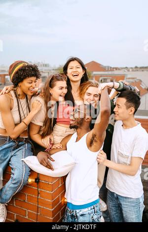 Felici amici maschi e femmine che si divertono insieme sul tetto Foto Stock