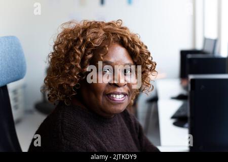 Imprenditrice sorridente seduto in ufficio Foto Stock