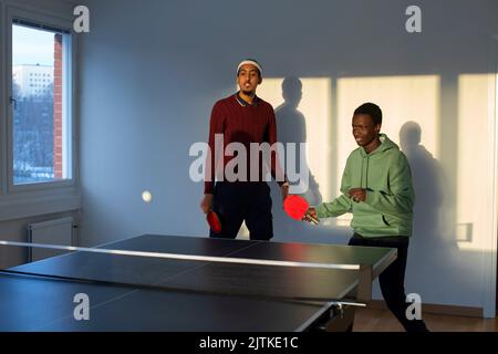 Amici che giocano a ping pong nella sala giochi Foto Stock