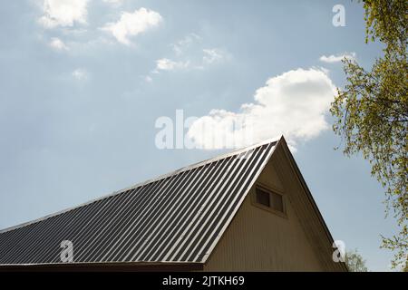 Tetto dell'edificio. Colmo tipo di tetto. Dettagli di piccola architettura. Edificio con piccole finestre. Foto Stock