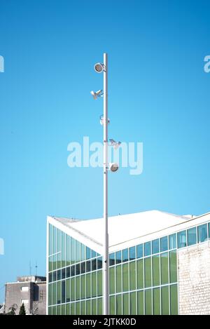 Un'immagine verticale di un palo della luce stradale con un edificio sullo sfondo Foto Stock