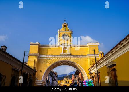 Bellissima ripresa aerea cinematografica della città di Antigua in Guatemala, la sua chiesa gialla, l'Arco di Santa Catalina e il vulcano Acatenango Foto Stock