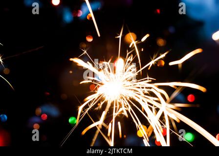 Bruciando le luci Bengala sull'albero di Natale sfondo chiaro contro le luci sfocate, primo piano Foto Stock