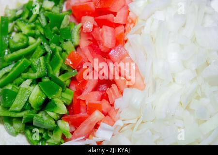 peperoni, pomodori e cipolle tritati su un tavolo. Foto Stock