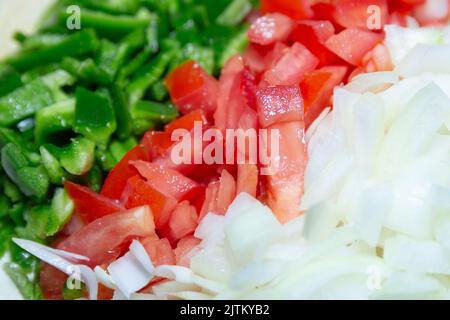 peperoni, pomodori e cipolle tritati su un tavolo. Foto Stock