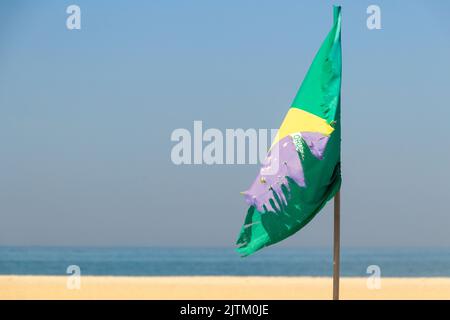 Bandiera brasiliana sbiadita e lacerata all'aperto sulla spiaggia di Copacabana a Rio de Janeiro. Foto Stock