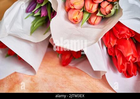 Tanti delicati bouquet di tulipani rossi e lilla, vista dall'alto. Un bouquet selezionato di bellissimi tulipani rossi in un package.The concetto di preparazione per Complimenti. Foto di alta qualità Foto Stock