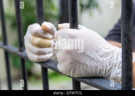 Mani che tengono una griglia durante la quarantena contro il coronavirus a Rio de Janeiro. Foto Stock