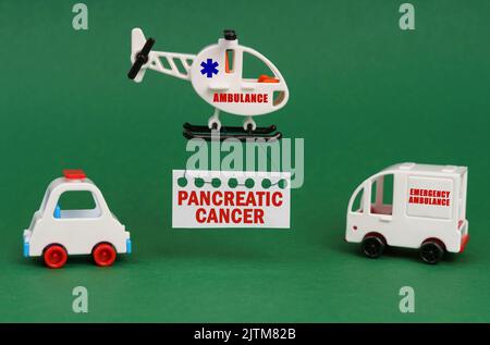 Concetto medico. Su una superficie verde, automobili e un elicottero ambulanza con un segno - cancro pancreatico Foto Stock