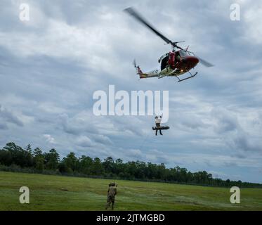 Uno Squadron di prova di volo 413th UH-1 Huey solleva due Airmen di Squadron di 20th di operazioni di supporto dell'aria nell'aria sopra Eglin Air Force base, Florida 23 agosto. Il 413th FLTS, l’unica unità di test per lo sviluppo di alari rotanti dell’Air Force, ha fornito un ulteriore realismo all’addestramento per l’estrazione di Airmen, il partito tattico per il controllo dell’aria. (STATI UNITI Foto dell'aeronautica/Samuel King Jr.) Foto Stock