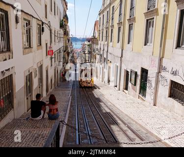 Coppia seduta e ammirando la scena mentre un tram si avvicina nella zona di Baixa-Chiado di Lisbona che si affaccia sul fiume Tago. Portogallo. Foto Stock