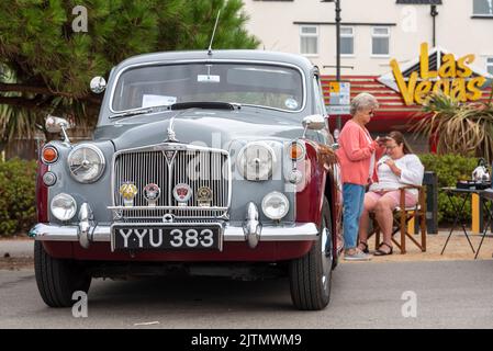 1960 Rover 100 berlina in mostra su Marine Parade, Southend on Sea, Essex, Regno Unito. Le donne, possibilmente soci dei proprietari, passando il tempo vicino. Posto a sedere nel campo Foto Stock