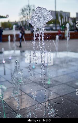 Un colpo verticale di acqua spruzza da una fontana in una città Foto Stock