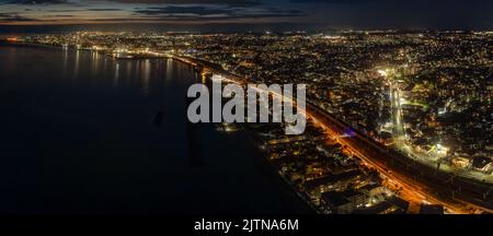 Vista aerea panoramica delle strade trafficate attraverso il paesaggio urbano costiero dopo il tramonto Foto Stock