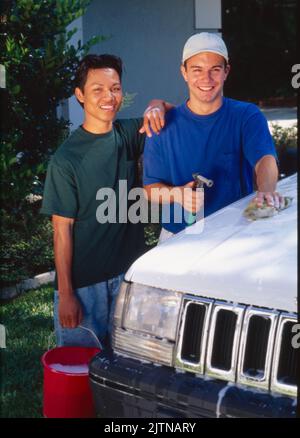 Due giovani gay che si divertono a lavare l'auto. Foto Stock