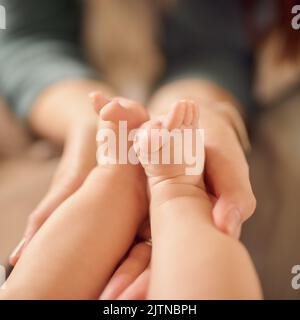 Le grandi storie iniziano con piccoli capitoli. Una madre non identificabile che tiene i piedi delle sue bambine. Foto Stock